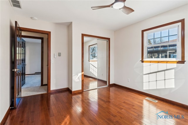 interior space featuring ceiling fan, dark wood-type flooring, and a baseboard heating unit