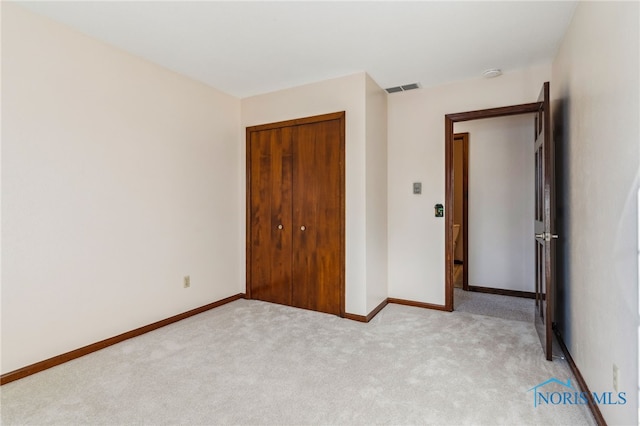 unfurnished bedroom with light carpet and a closet