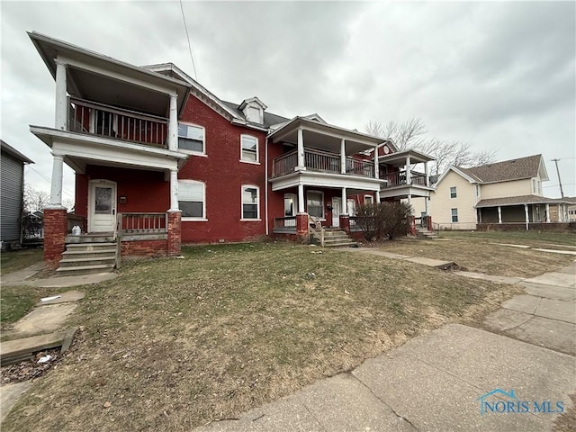 view of front of property with a balcony, a porch, and a front yard