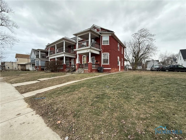 view of front facade featuring a balcony, covered porch, and a front yard