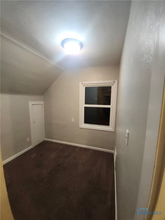 bonus room featuring dark carpet and lofted ceiling