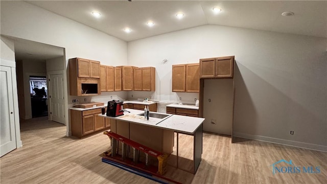 kitchen with sink, high vaulted ceiling, a center island with sink, and light wood-type flooring