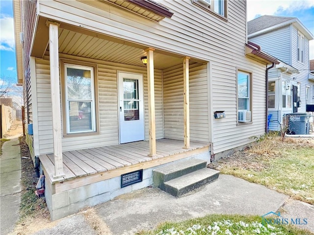 view of exterior entry featuring covered porch and cooling unit