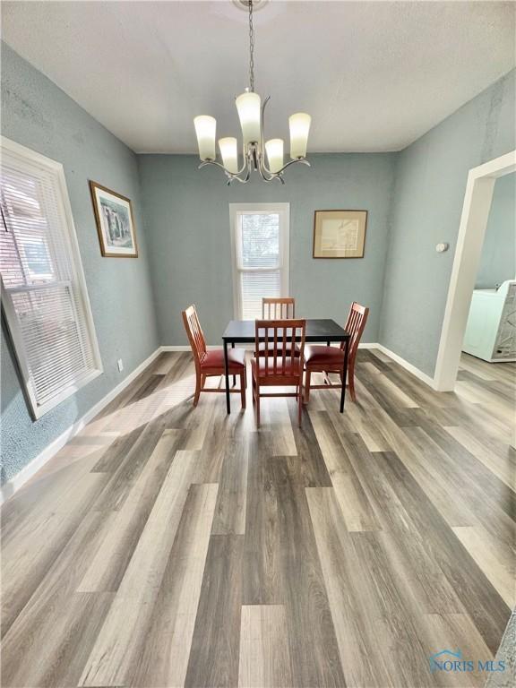 dining area featuring wood-type flooring and an inviting chandelier