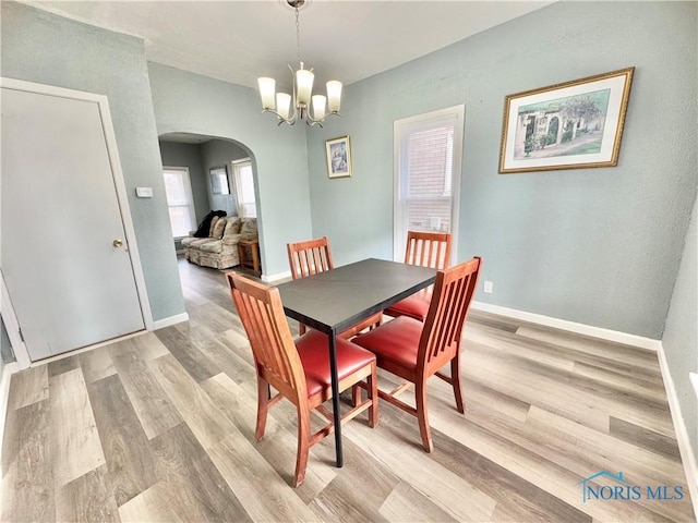 dining area with light hardwood / wood-style floors and a chandelier