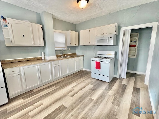 kitchen featuring a textured ceiling, white cabinetry, sink, and white appliances