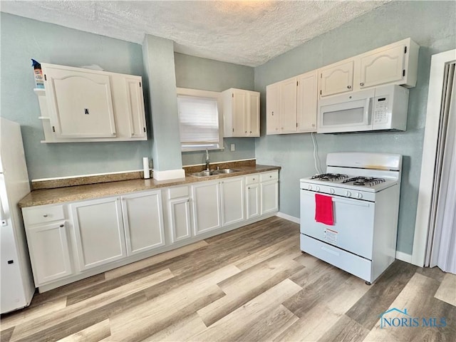 kitchen with white cabinetry, white appliances, and a textured ceiling