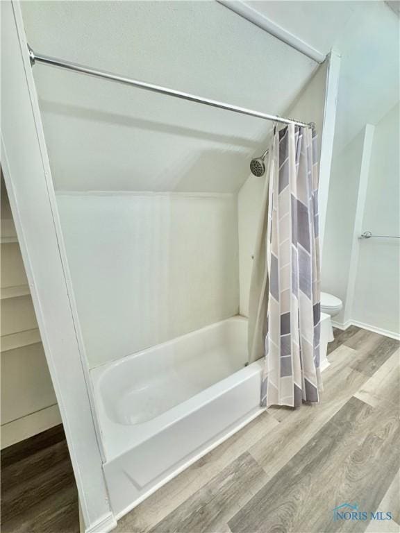 bathroom with hardwood / wood-style flooring, toilet, shower / bathtub combination with curtain, and lofted ceiling