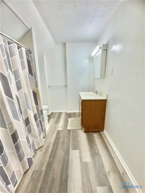 bathroom featuring vanity, wood-type flooring, a textured ceiling, and toilet