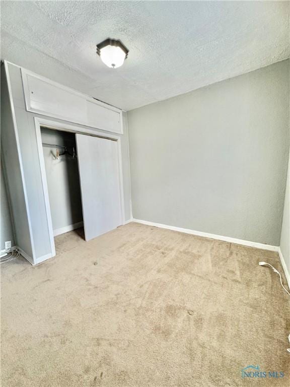 unfurnished bedroom with a textured ceiling, carpet floors, and a closet