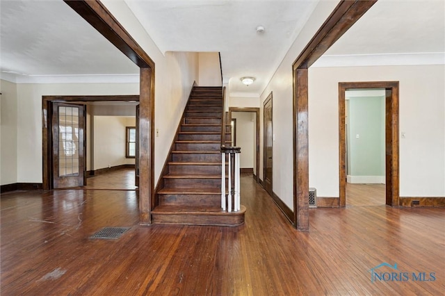 stairway with ornamental molding and hardwood / wood-style floors