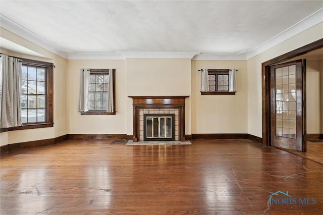 unfurnished living room with dark wood-type flooring, a tile fireplace, and ornamental molding