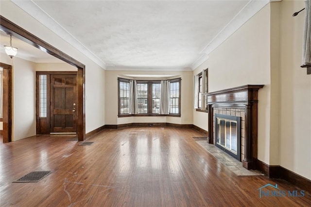 unfurnished living room with ornamental molding, hardwood / wood-style flooring, and a tile fireplace