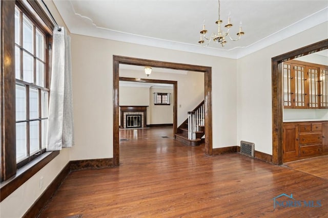 interior space with dark wood-type flooring, plenty of natural light, crown molding, and a notable chandelier