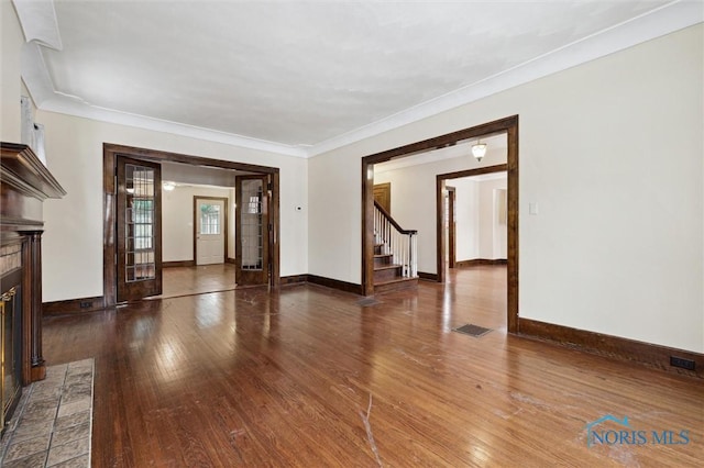 unfurnished living room featuring dark hardwood / wood-style flooring, ornamental molding, and a fireplace