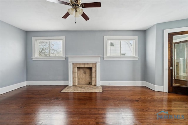 unfurnished living room with ceiling fan, dark wood-type flooring, and a tile fireplace