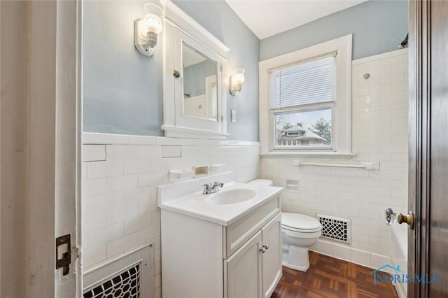 bathroom featuring parquet flooring, tile walls, toilet, and vanity