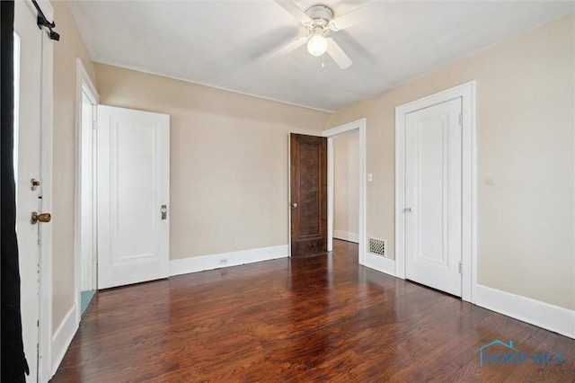 unfurnished bedroom with ceiling fan, dark hardwood / wood-style flooring, and a barn door