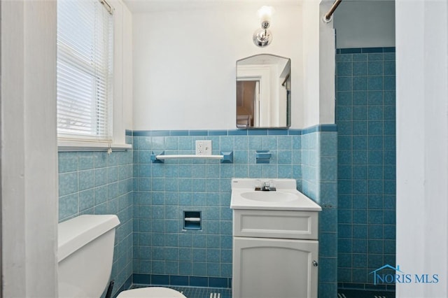 bathroom with toilet, vanity, and tile walls