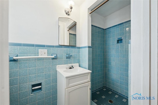 bathroom featuring tile walls, tiled shower, and vanity