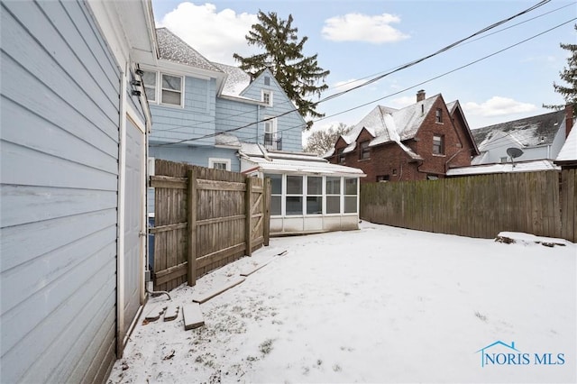 yard covered in snow with a sunroom