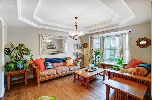 living room featuring crown molding, hardwood / wood-style flooring, a raised ceiling, and a chandelier