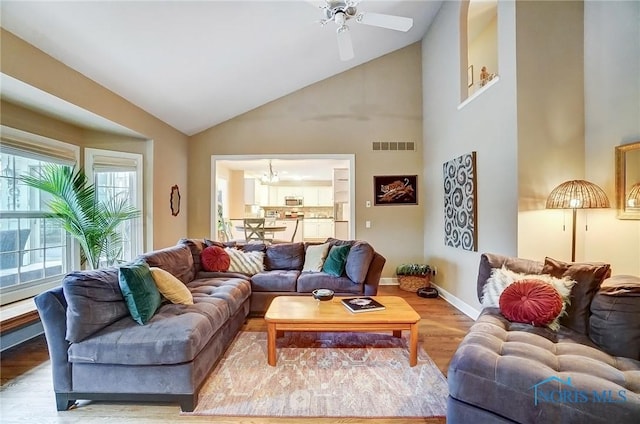 living room with ceiling fan, high vaulted ceiling, and light hardwood / wood-style floors