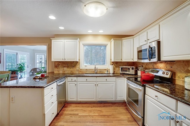 kitchen featuring white cabinetry, sink, kitchen peninsula, and appliances with stainless steel finishes