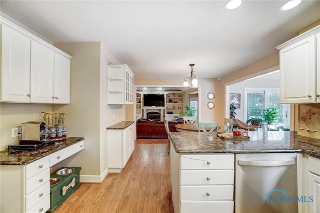 kitchen with dark stone countertops, light wood-type flooring, hanging light fixtures, and white cabinets