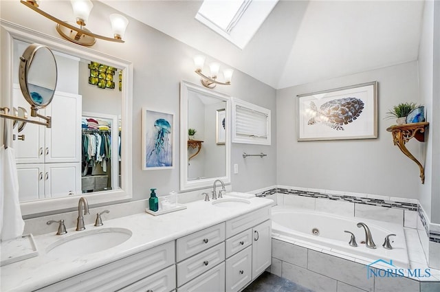 bathroom featuring vanity, lofted ceiling with skylight, and tiled bath