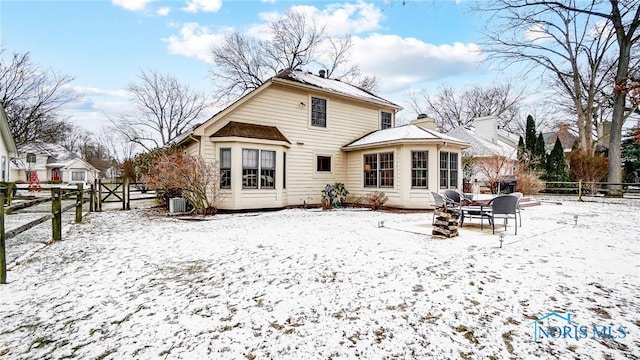 snow covered back of property featuring central AC unit