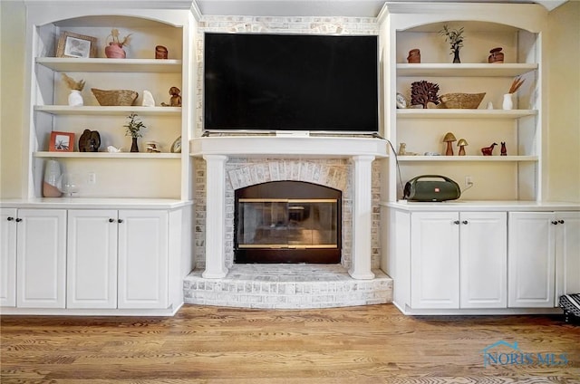 unfurnished living room with a brick fireplace and light hardwood / wood-style floors