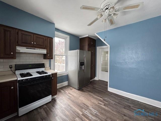 kitchen featuring ceiling fan, white gas stove, dark hardwood / wood-style flooring, backsplash, and stainless steel fridge