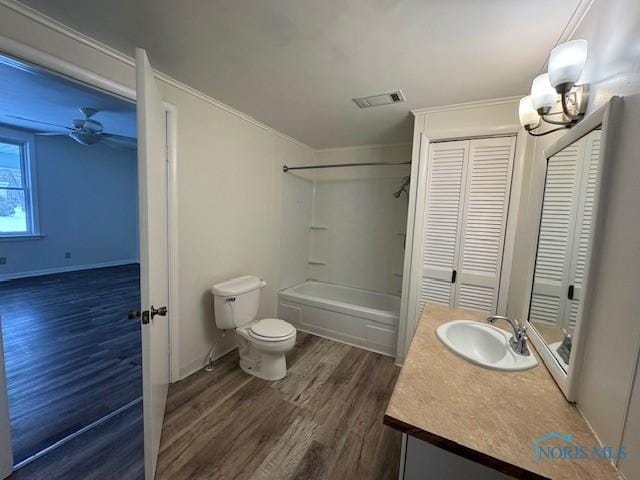 full bathroom featuring ornamental molding, vanity, washtub / shower combination, hardwood / wood-style floors, and toilet