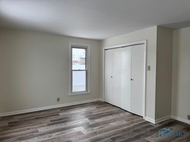 unfurnished bedroom featuring a closet and dark wood-type flooring