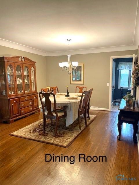 dining space with ornamental molding, dark wood-type flooring, and a chandelier