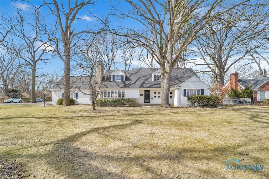new england style home featuring a chimney and a front yard