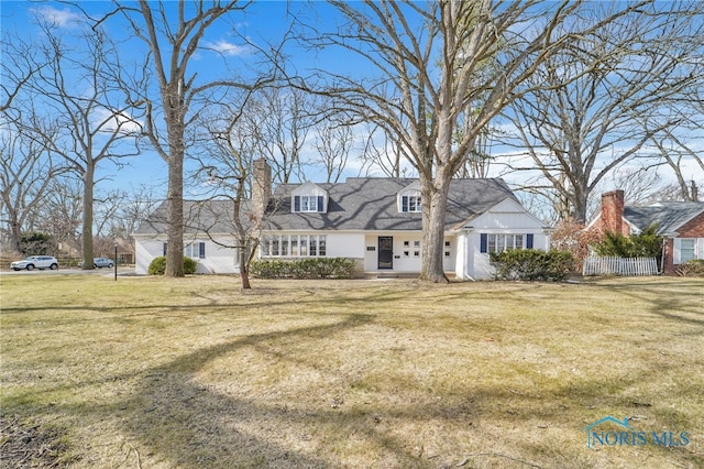 new england style home featuring a chimney and a front yard