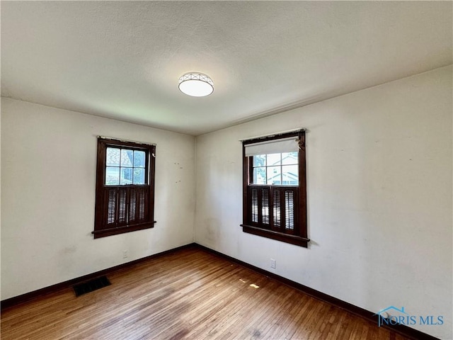 empty room with hardwood / wood-style floors and a healthy amount of sunlight