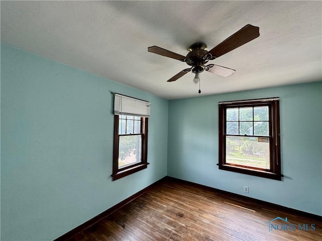 empty room featuring dark hardwood / wood-style floors, a healthy amount of sunlight, a textured ceiling, and ceiling fan