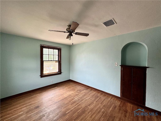 empty room featuring ceiling fan, wood-type flooring, and a textured ceiling