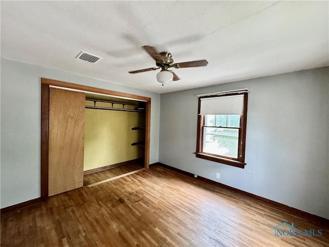 unfurnished bedroom featuring hardwood / wood-style floors, ceiling fan, and a closet