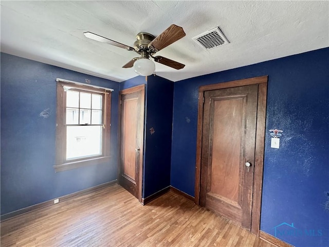 unfurnished bedroom featuring ceiling fan, light hardwood / wood-style floors, and a textured ceiling