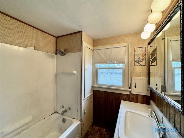 bathroom with wooden walls, sink, and tub / shower combination