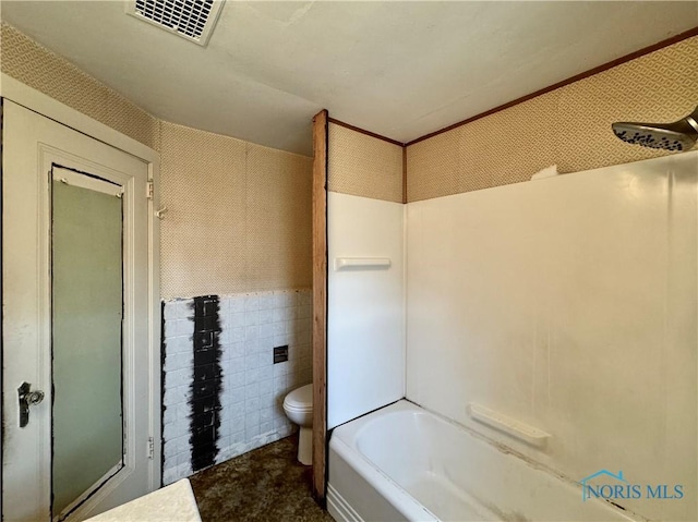 bathroom with toilet and tile walls