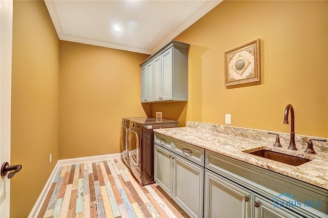 clothes washing area with sink, cabinets, washing machine and dryer, crown molding, and light wood-type flooring