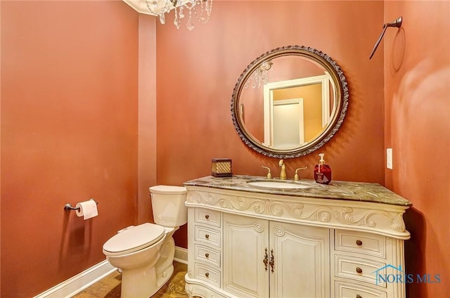 bathroom with a chandelier, vanity, hardwood / wood-style flooring, and toilet