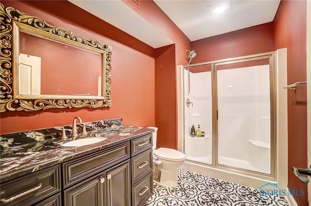 bathroom featuring tile patterned floors, vanity, toilet, and a shower with shower door