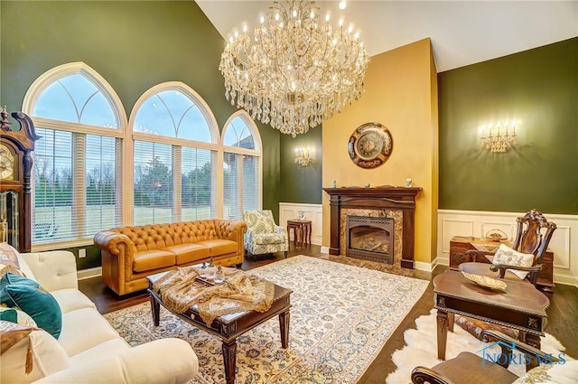 living room with hardwood / wood-style flooring, a fireplace, high vaulted ceiling, and an inviting chandelier