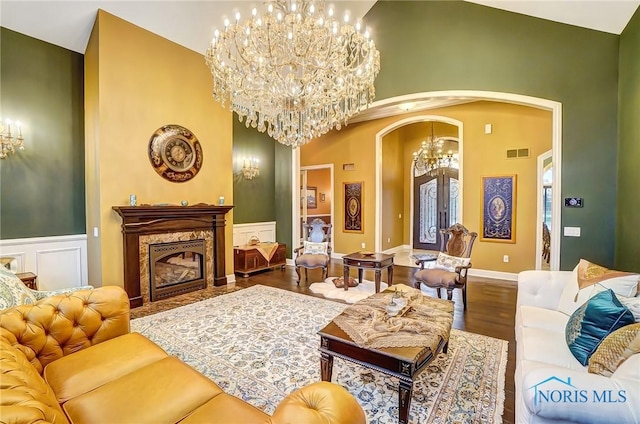 living room with a high end fireplace, hardwood / wood-style floors, high vaulted ceiling, and an inviting chandelier